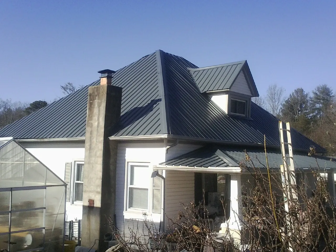 Dark blue standing seam metal roof on a white farmhouse with dormer — Slate & Tile Roof Repair by Roofing Brothers in Arion