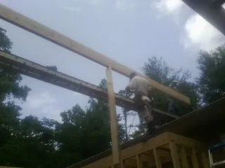 Carpenter setting a ridge beam over a new addition frame — Ice Dam Removal by Roofing Brothers in Arion