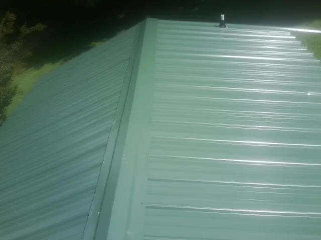 New green metal panels meeting at the ridge of a roof — Flat Roof Repair work by our crew in Arion