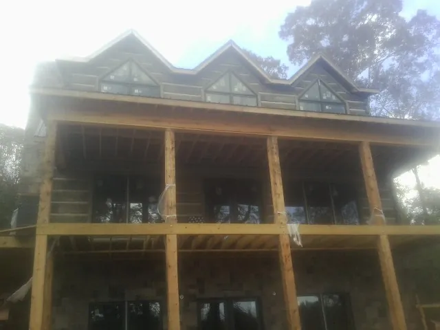 Dormers and porch framing on a large log home under construction — Roof Coating work by our crew in Arion