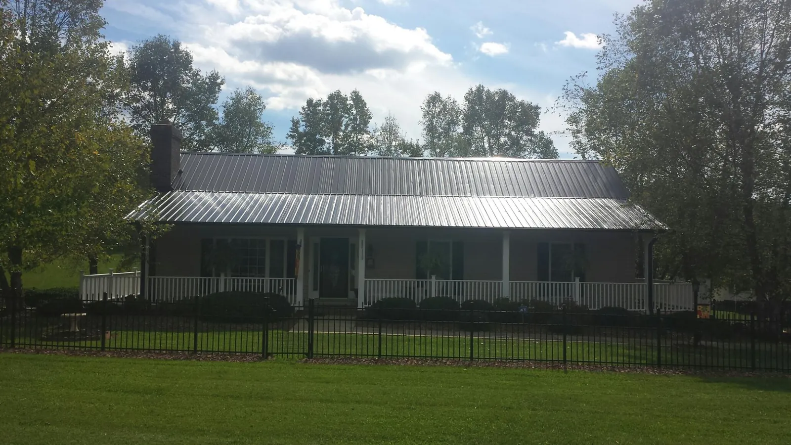 Gray metal roof on a brick ranch with a full width front porch — Gutter Guard Installation work by our crew in Arion