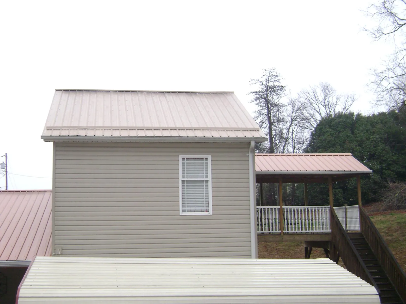 Tan metal roofs on a two story addition and attached porch, from a Roof Replacement job in Arion