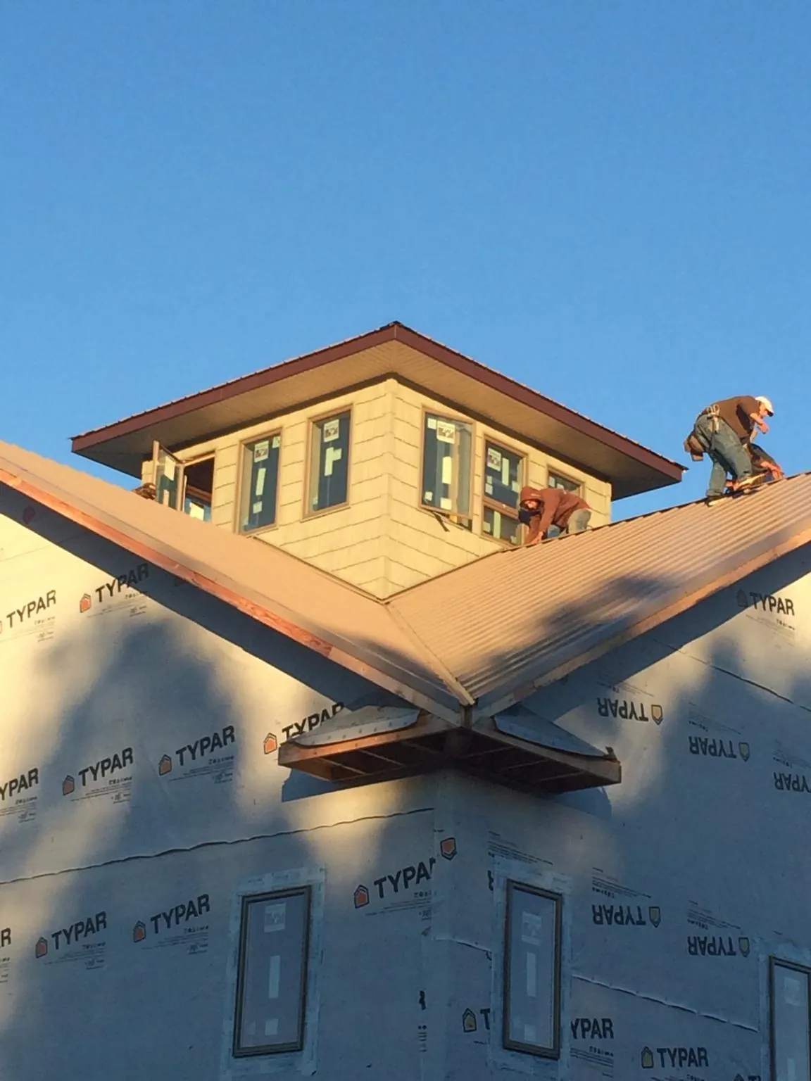 Roofers working around a rooftop cupola on a new metal roof at sunset — Roof Waterproofing in Arion by Roofing Brothers